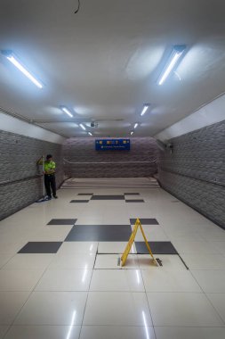 Jakarta, Endonezya - 9 Şubat 2025: Adam tren istasyonunda bir altgeçidi temizliyor. İstasyon boş ve duvarlar kiremitlerle kaplı.