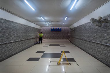 Jakarta, Endonezya - 9 Şubat 2025: Adam tren istasyonunda bir altgeçidi temizliyor. İstasyon boş ve duvarlar kiremitlerle kaplı.
