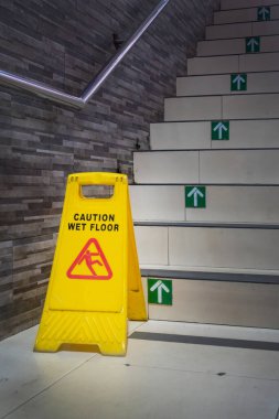 Sarı uyarı işareti basamakta. İşaret insanları ıslak zeminde dikkatli olmaları konusunda uyarıyor.