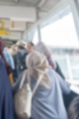 Kalabalık bir tren istasyonunun yürüyen merdiveninin bulanık görüntüsü ve tesettürlü insanlar. Sahne meşgul ve hareketli.