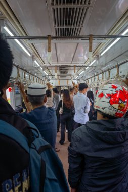Kasklı bir adam kalabalık bir metroda seyahat ederken cep telefonu tutuyor. Kentsel hayat kavramı ve modern toplumun hızlı doğası.