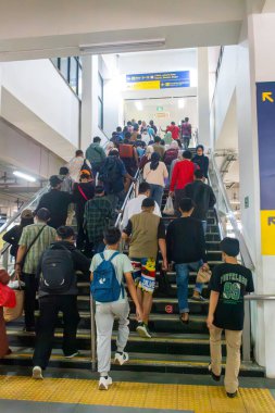 Cakarta, Endonezya-Şubat 9.2025: Bir grup insan Manggarai tren istasyonunda bir dizi merdivenden yukarı çıkıyorlar. Sahne meşgul ve hareketli, insanlar merdivenlerden çıkarken çantalarını taşıyorlar.