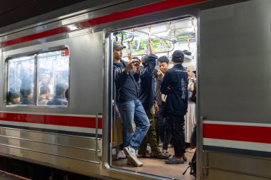 Jakarta, Endonezya - 9 Şubat 2025: Bir grup insan trene biniyor. Bir adam telefon tutuyor. Sahne meşgul ve hareketli.