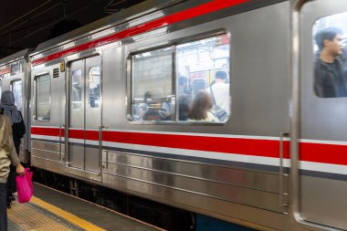 Jakarta, Endonezya - 9 Şubat 2025: Gümüş ve kırmızı tren insanların inip çıktığı tren. Tren kalabalık ve insanlar sırt çantası takıyor.