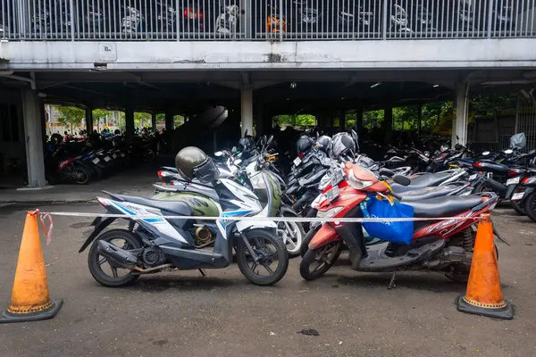 Jakarta, Endonezya - 9 Şubat 2025: Motosikletler bir otoparka park edilmiştir. Otopark motosikletlerle dolu ve turuncu koni kuyruğu var. Pondok Ranji tren istasyonu.