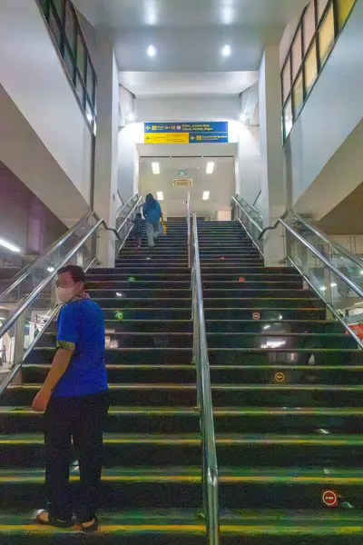 Jakarta, Endonezya - 9 Şubat 2025: Mavi gömlekli adam merdivenlerden yukarı çıkıyor. Manggarai tren istasyonunda merdivenler çok uzundur.