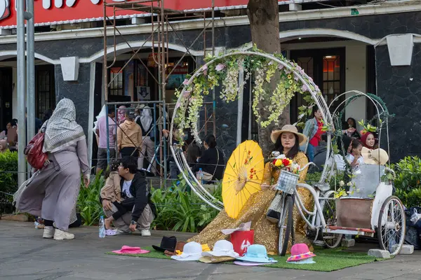 Jakarta, Endonezya - 9 Şubat 2025: Bir grup insan Mixue adında bir mağazanın önünde caddede yürüyorlar. Kaldırımda oturan birkaç kişi var. Sahne canlı ve hareketli.