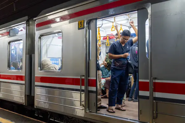 Jakarta, Endonezya - 9 Şubat 2025: Bir grup insan trene biniyor. Bir adam askı çantası tutuyor. Sahne meşgul ve hareketli.
