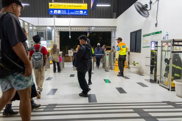 Jakarta, Endonezya - 9 Şubat 2025: Bir grup insan bir tren istasyonunda yürüyor. Grubun ortasında sarı yelekli bir güvenlik var.