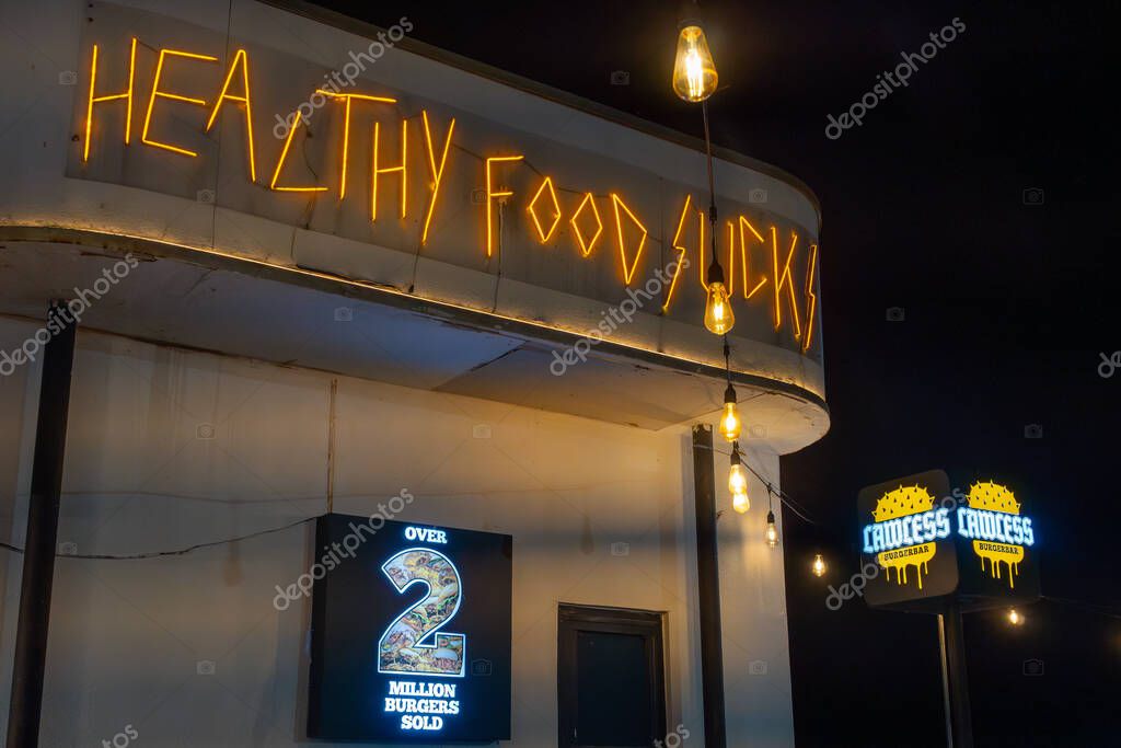 Jakarta, Indonesia - February 9, 2025: Restaurant with a neon sign that says Lawless. There are tables and chairs outside and inside