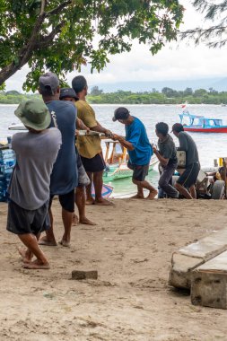Gili Trawangan, Endonezya - 4 Ocak 2025: Bir grup adam sıra sıra bir araba çekiyor. Ön planda birkaç bisiklet var.