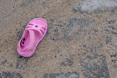 Pembe sandalet yerde yatıyor. Sandalet kirli ve siyah beyaz bir tasarımı var. Sandalet terk edilip arkada bırakıldığı için görüntüde hüzünlü ve yalnız bir ruh hali var.