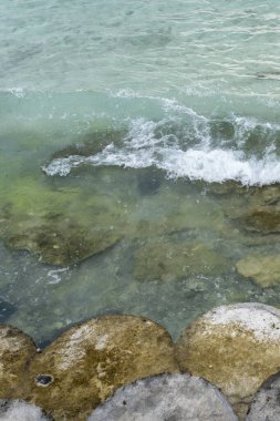 Su sakin ve berrak, kayalık bir kıyı şeridi var. Kayalar kahverengi ve beyazdır ve su koyu mavi renktedir.