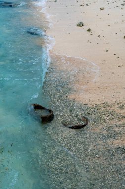 Okyanus sakin ve sahil kayalık. Su mavi ve kayalar sahile saçılmış.
