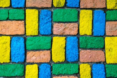 Ortasında sarı tuğla olan renkli tuğla bir duvar. Duvar mavi, yeşil ve sarı olmak üzere farklı renkli tuğlalardan yapılmıştır.