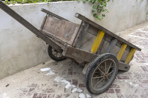 Gili Trawangan, Endonezya - 4 Ocak 2025: Sarı ve siyah tekerlekli ahşap araba duvara yaslanıyor. Araba eski ve kırsal bir görünüşü var.