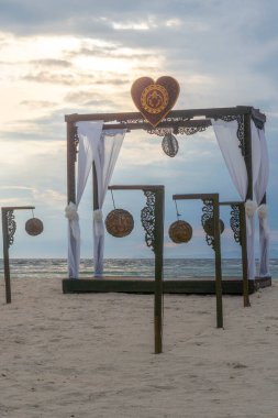 Sahilde bir pavyon ve birkaç asılı fener sahnesi. Çadır ahşap bir çitle çevrili ve fenerler çitlerden sarkıyor. Huzurlu bir sahne.