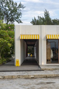 Sarı ve beyaz tenteli ve kaldırımında sarı işareti olan bir bina.