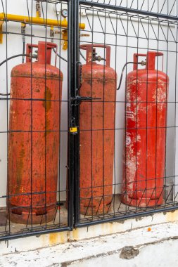 Dört kırmızı gaz tankı bir duvara zincirlenmiş. Tanklar paslı ve eski. Tehlike ve ihtiyat kavramı, tanklar kullanımda değil ve yanlış kullanılırsa potansiyel olarak patlayabilir.