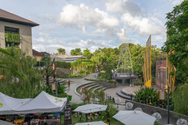 Bali, Endonezya - 23 Aralık 2024: Bir grup insan bir parkta şemsiyelerin altında masalarda oturuyor. Şemsiyeler beyaz ve onlardan çok var. İnsanlar dışarıda eğleniyor.