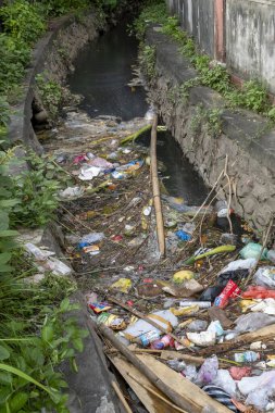 Bali, Endonezya - 23 Aralık 2024: Kirli, kirlenmiş nehir içinde çöp ve enkaz yüzüyor. İhmal ve çevreyi önemsememe kavramı