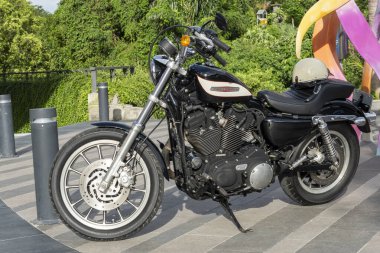 Bali, Endonezya - 23 Aralık 2024: Siyah-beyaz Harley Davidson motosikleti bir binanın önünde park halinde..