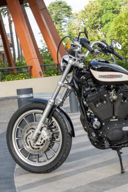 Bali, Endonezya - 23 Aralık 2024: Siyah-beyaz Harley Davidson motosikleti bir binanın önünde park halinde..