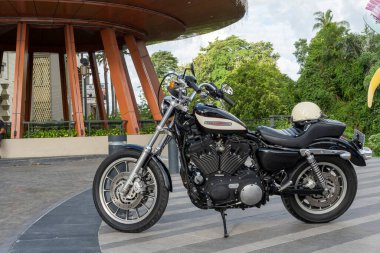 Bali, Endonezya - 23 Aralık 2024: Siyah-beyaz Harley Davidson motosikleti bir binanın önünde park halinde..