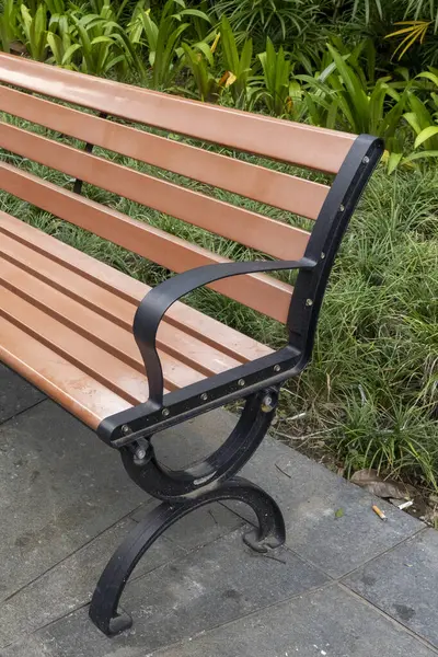 Tahta bank bir çalılığın önünde duruyor. Banklar boş, çalılar yeşil.