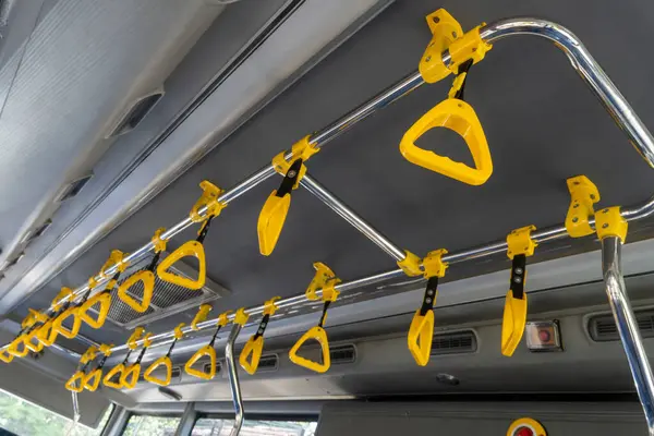 Otobüsün yolcuların tutunması için sarı sapları var. Kollar metal bir çubuğa bağlı ve trenin uzunluğu boyunca eşit aralıklarla uzanıyor.