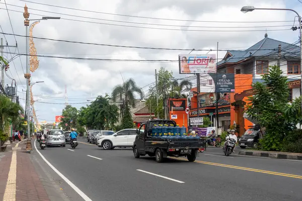 Bali, Endonezya - 23 Aralık 2024: Su şişeleri taşıyan bir kamyonla dolu bir cadde. Kamyon diğer arabalar ve motosikletlerle caddede ilerliyor.