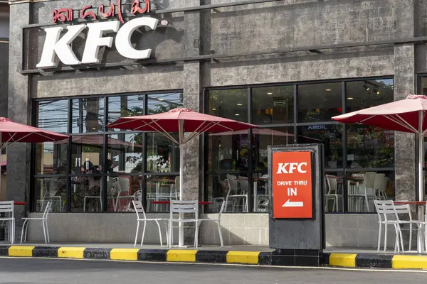 Bali, Endonezya - 23 Aralık 2024: 24 Büyük KFC restoranı. Binanın etrafı ağaçlarla çevrili ve kırmızı ve beyaz bir tabela var.
