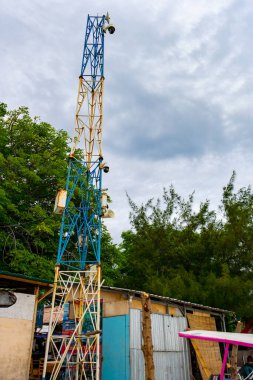 Gili, Lombok, Endonezya - 3 Ocak 2025: Mavi ve sarı kapaklı uzun kule. Gökyüzü bulutlu ve ağaçlar yeşil
