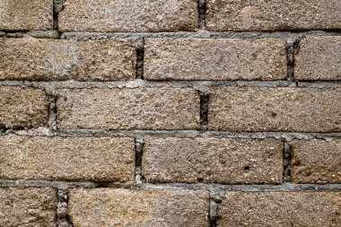 Kabataslak desenli tuğla duvar ve birkaç delik. Duvar gri tuğlalardan yapılmış ve biraz yıpranmış görünüyor.