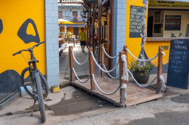 Gili, Lombok, Endonezya - 3 Ocak 2025: Bisiklet sarı duvarlı bir binanın yanına park edilmiştir. Bir adam geçiyor. Binada 