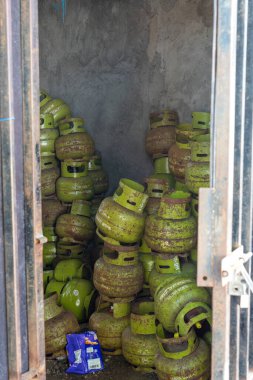Gili, Lombok, Endonezya - 3 Ocak 2025: Yeşil gaz tankları bir odaya istiflenmiştir. Oda karanlık ve tanklar üst üste yığılmış.