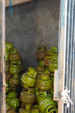 Gili, Lombok, Endonezya - 3 Ocak 2025: Yeşil gaz tankları bir odaya istiflenmiştir. Oda karanlık ve tanklar üst üste yığılmış.