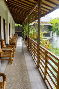 Korkuluklu ahşap balkon ve asılı havlu. Balkonda bir sürü sandalye var..