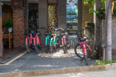 Gili, Lombok, Endonezya - 3 Ocak 2025: Bisikletler bir binanın önünde park halinde. Bisikletler pembe ve yeşil.