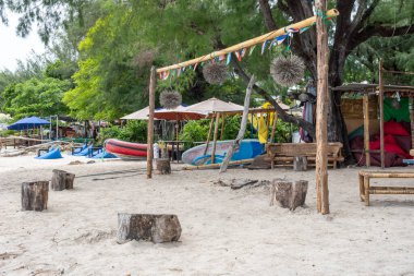 Gili, Lombok, Endonezya - 3 Ocak 2025: Birkaç şemsiye ve birkaç bank ile sahil. Kumsal boş.