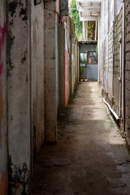 Bir tarafında tuğla duvar olan dar bir sokak. Duvar grafiti ile kaplı ve sokak boş.