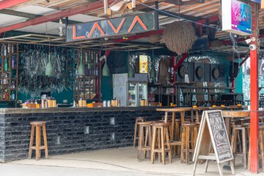 Gili, Lombok, Endonezya - 3 Ocak 2025: Duvarında lav işareti olan bar. Tahta tabureler ve masalar var. Bar boş.