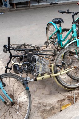 Gili, Lombok, Endonezya - 3 Ocak 2025: Kaldırıma bir sıra bisiklet park edilmiş, bisikletlerden biri devrilmişti, bazıları bakımsızdı. İhmal ve terk etme kavramı.