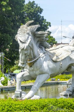 Bali, Endonezya - 19 Aralık 2024: bir at heykeli ve sırtında iki adam. Heykel yemyeşil bir park ile çevrili.