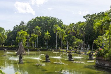 Bali, Endonezya - 19 Aralık 2024: Üzerinde iki ejderha heykeli olan güzel bir çeşme. Çeşme yemyeşil bir bahçeyle çevrilidir.
