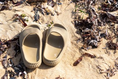 İki bronz sandalet kumun üzerinde yatıyor. Sandaletler kullanılmıyor ve geride bırakılıyor.