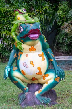 Bali, Endonezya - 19 Aralık 2024: Üzerinde bir kurbağa olan kurbağa heykeli. Üstteki kurbağa yeşil, alttaki kurbağa sarı.