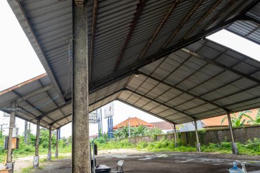 Büyük, boş bir bina, yanında da bir tabela var. Çatı metalden yapılmış ve bina ağaçlarla çevrili.