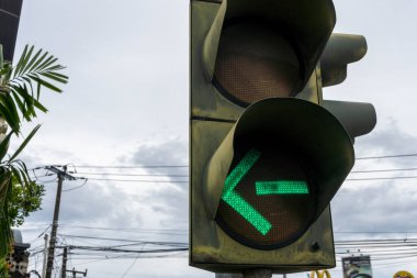 Bali, Endonezya - 25 Aralık 2024: Üzerinde yeşil ok bulunan trafik ışığı yanıyor, bu da sürücülerin sola dönmesi gerektiğini gösteriyor.
