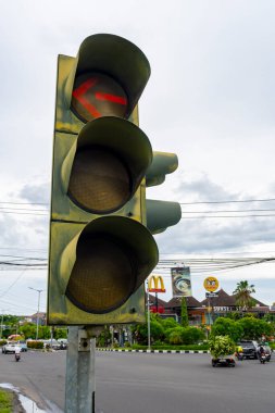 Bali, Endonezya - 25 Aralık 2024: Üzerinde kırmızı ok bulunan trafik ışığı yanıyor, bu da sürücülerin sola dönmesi gerektiğini gösteriyor. Kırmızı ışık yanıyor, yani sürücüler durmalı.